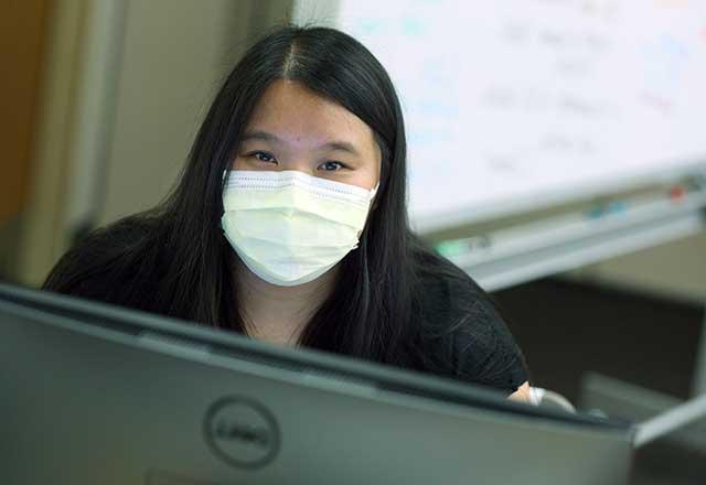 Employee wearing a mask and looking at a computer.